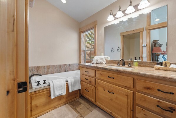 A bathroom with wooden cabinetry, a large mirror, and a sink with a faucet.