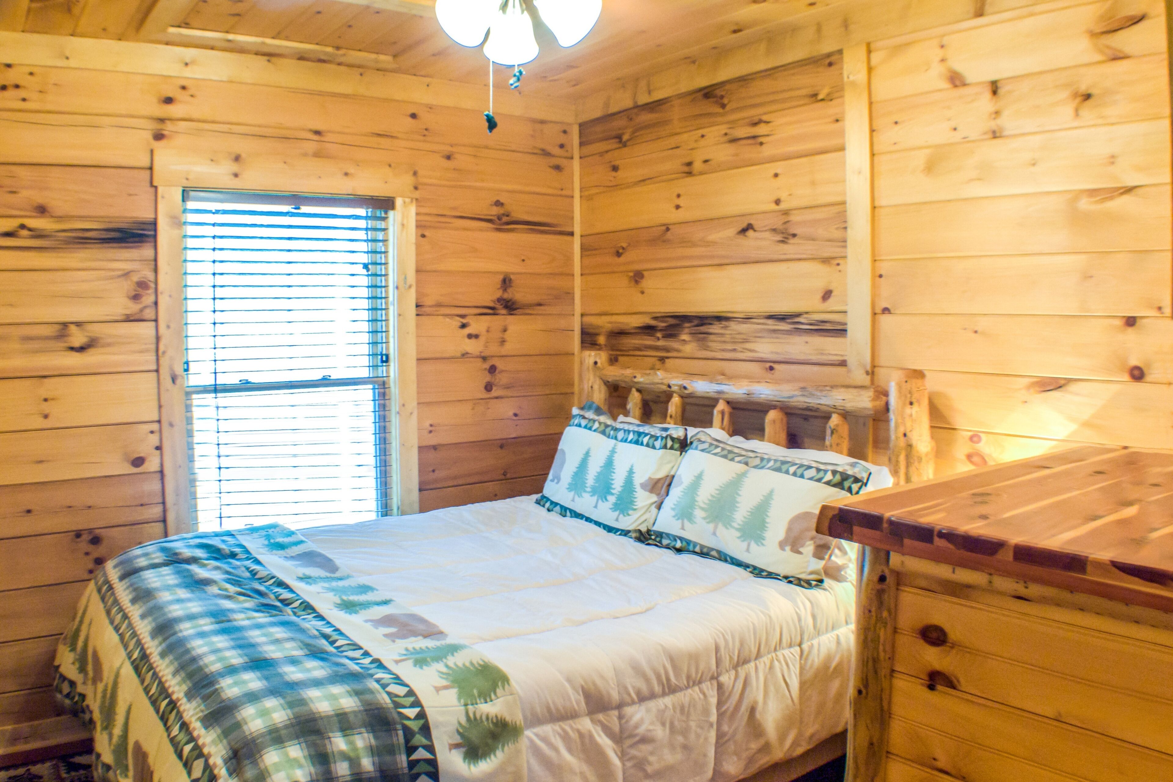 Une chambre dans une cabane en bois, avec un lit, une fenêtre et une commode.