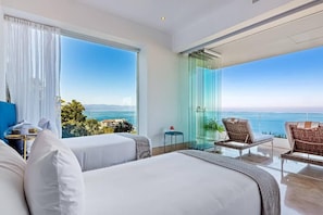 A hotel room with a large balcony, a bed, a small table, and a chair.