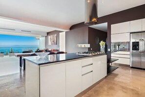 Una cocina moderna con una isla grande, electrodomésticos de acero inoxidable y vistas al mar.