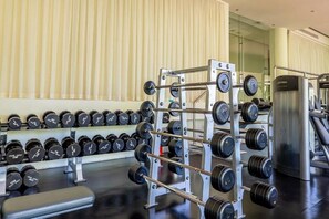 A gym with weightlifting equipment, including dumbbells and a barbell rack.