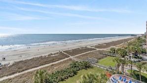 A beach view with a boardwalk, palm trees, and a pier in the distance. - BEACHFRONT-Remodeled 200 + 5-star reviews-  Best LOCATION  River- 6th Floor  (Myrtle Beach)