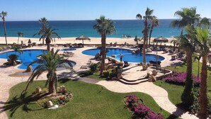 Un complex turístic amb diverses piscines, palmeres i vistes a la platja.