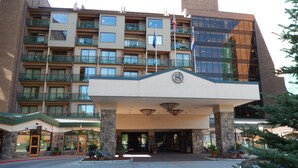 Ein Hotel mit modernem Eingang, mehreren Balkonen und einer Fahnenstange.