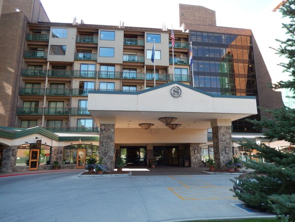 A hotel with a modern entrance, multiple balconies, and a flagpole.