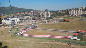 Ein Skigebiet mit Seilbahn, Gebäuden und einer kurvenreichen Straße.