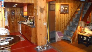 A wooden interior with a kitchen, dining area, and staircase.
