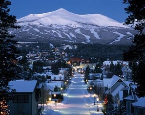 Une rue enneigée qui mène à une montagne dont le sommet est coiffé de neige.