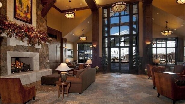 A spacious lobby with a stone fireplace, comfortable seating, and large windows offering a view of the outdoors. - Breckenridge Christmas & New Year weeks 2021-2022 email (Breckenridge)