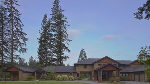 A building with multiple entry points, surrounded by tall trees, and a well-maintained lawn. - Close-in Beautiful Retreat: Large, Lodge-Like Private Lakefront Setting (Renton)