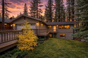 Un chalet à deux étages doté d’une terrasse, d’un garage et d’un petit porche.