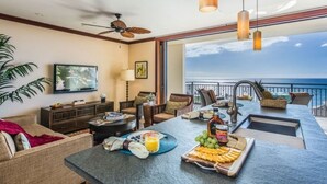A modern living room with a dining area, large windows, and a view of the ocean.