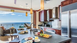 A modern kitchen with a large island, stainless steel appliances, and a view of the ocean.