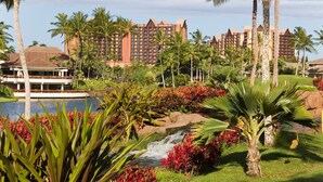 A resort with a pool, palm trees, and a waterfall.
