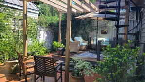 Eine Terrass mit Holzmöbeln, einer Pergola und Kübelpflanzen.