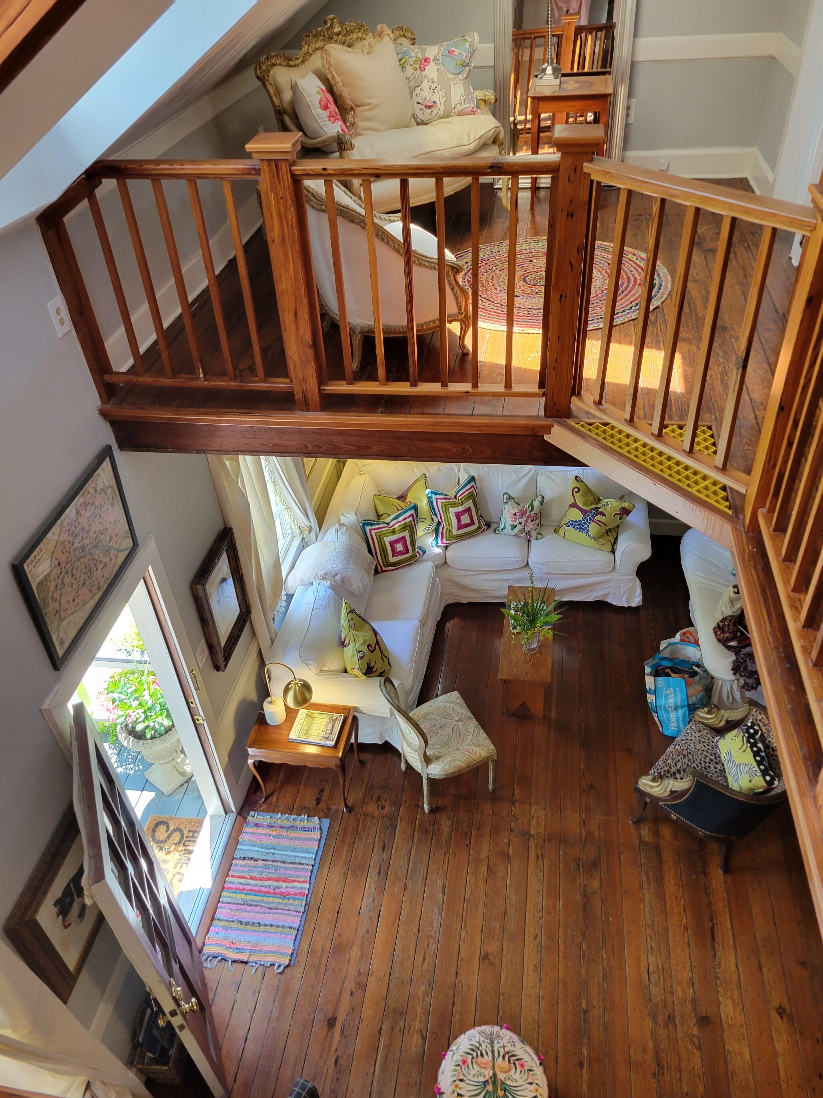 Amplia zona de estar tipo loft con una escalera de madera, un conjunto de sofá blanco y una pequeña mesa de comedor.