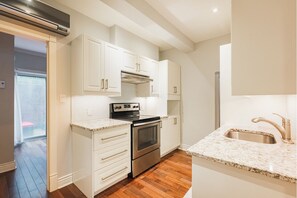 Una cocina moderna con armarios blancos, horno de acero inoxidable y encimera de granito.