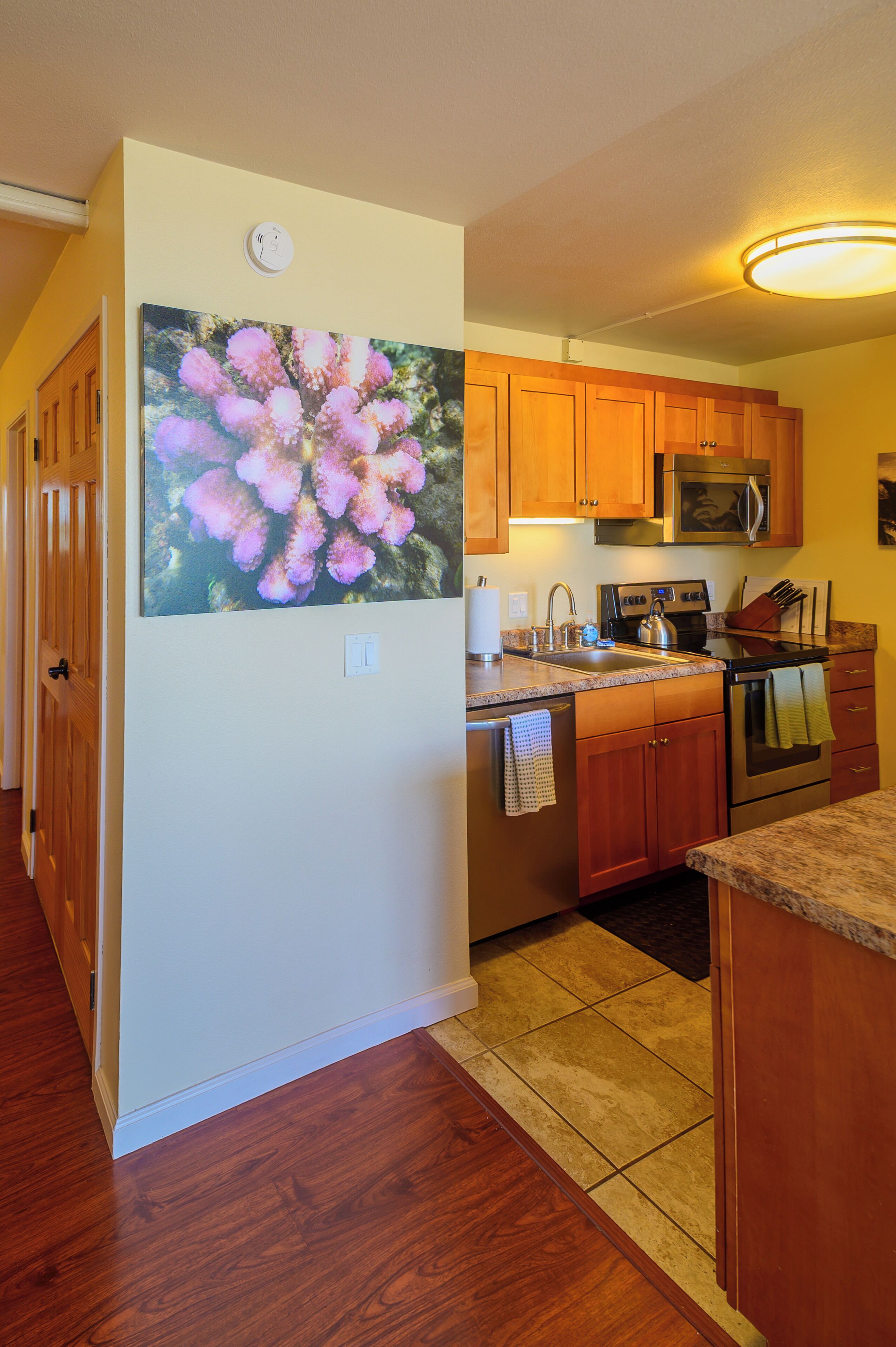 A kitchen with wooden cabinets, a stainless steel refrigerator, a microwave, and a stove.