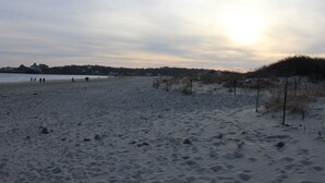 Ein Strand mit Sand, einigen Personen und einem Sonnenuntergang.