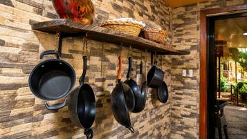 Een keuken met hangende pannen en potten, een houten plank met manden, en een muur met een stenen patroon.