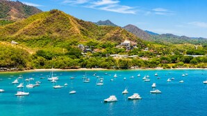 A coastal area with numerous boats in the water, a beach, and a hillside with buildings. - Casa Melosa Villa in Playa Potrero/Flamingo Costa Rica (Playa Potrero/Flamingo)