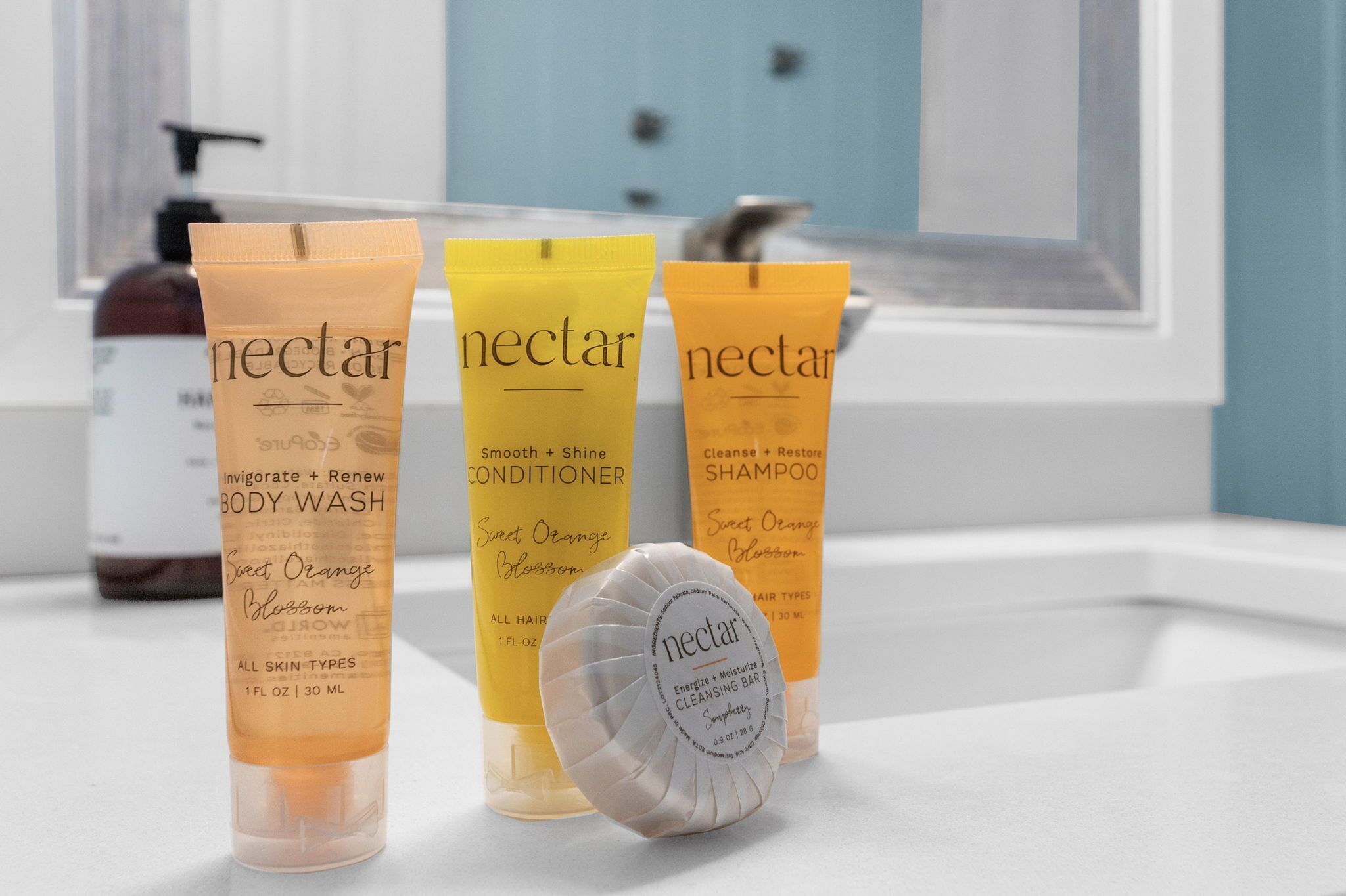 Three bottles of Nectar body wash, conditioner, and shampoo on a bathroom counter.