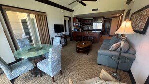 A hotel room with a dining table, two armchairs, a sofa, a small round table, a bar area, and a ceiling fan. - AMAZING PRIME OCEANVIEW 2 BDRM, 3 BATH PENTHOUSE (Kapaa)