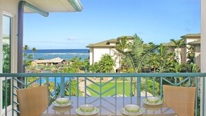 A balcony with wicker furniture, a glass table, and a view of the ocean and resort buildings. - AMAZING PRIME OCEANVIEW 2 BDRM, 3 BATH PENTHOUSE (Kapaa)