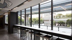 Zona de bar moderna con ventanas altas y vistas a la ciudad.