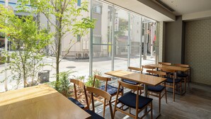 A restaurant with wooden tables and chairs, large windows offering a view of the street. - Hotel Oriental Express Tokyo Kamata (Tokyo)