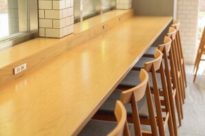 A long wooden table with grey cushioned chairs. - Hotel Oriental Express Tokyo Kamata (Tokyo)