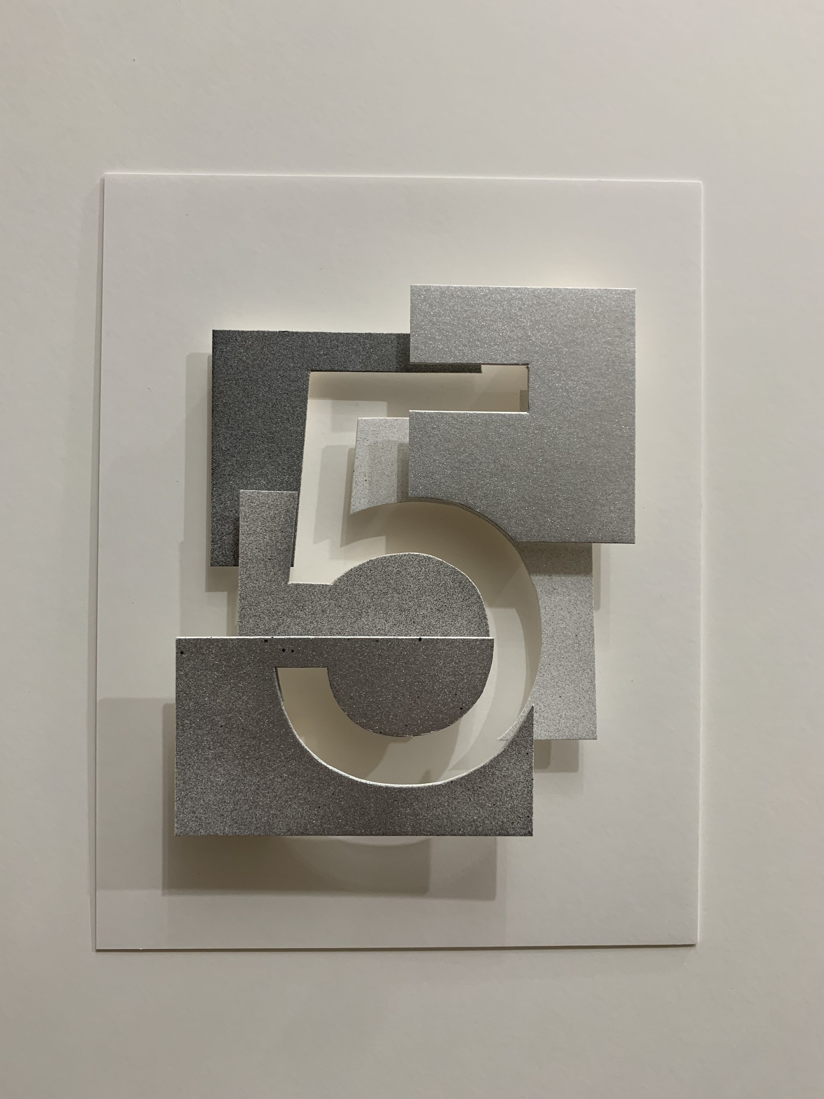 A geometric art piece with a large number '5' and smaller shapes on a white background.