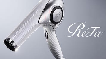 A hair dryer with a transparent handle and a metallic body, featuring a control dial with settings.