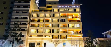A multi-story hotel with illuminated signage and balconies.