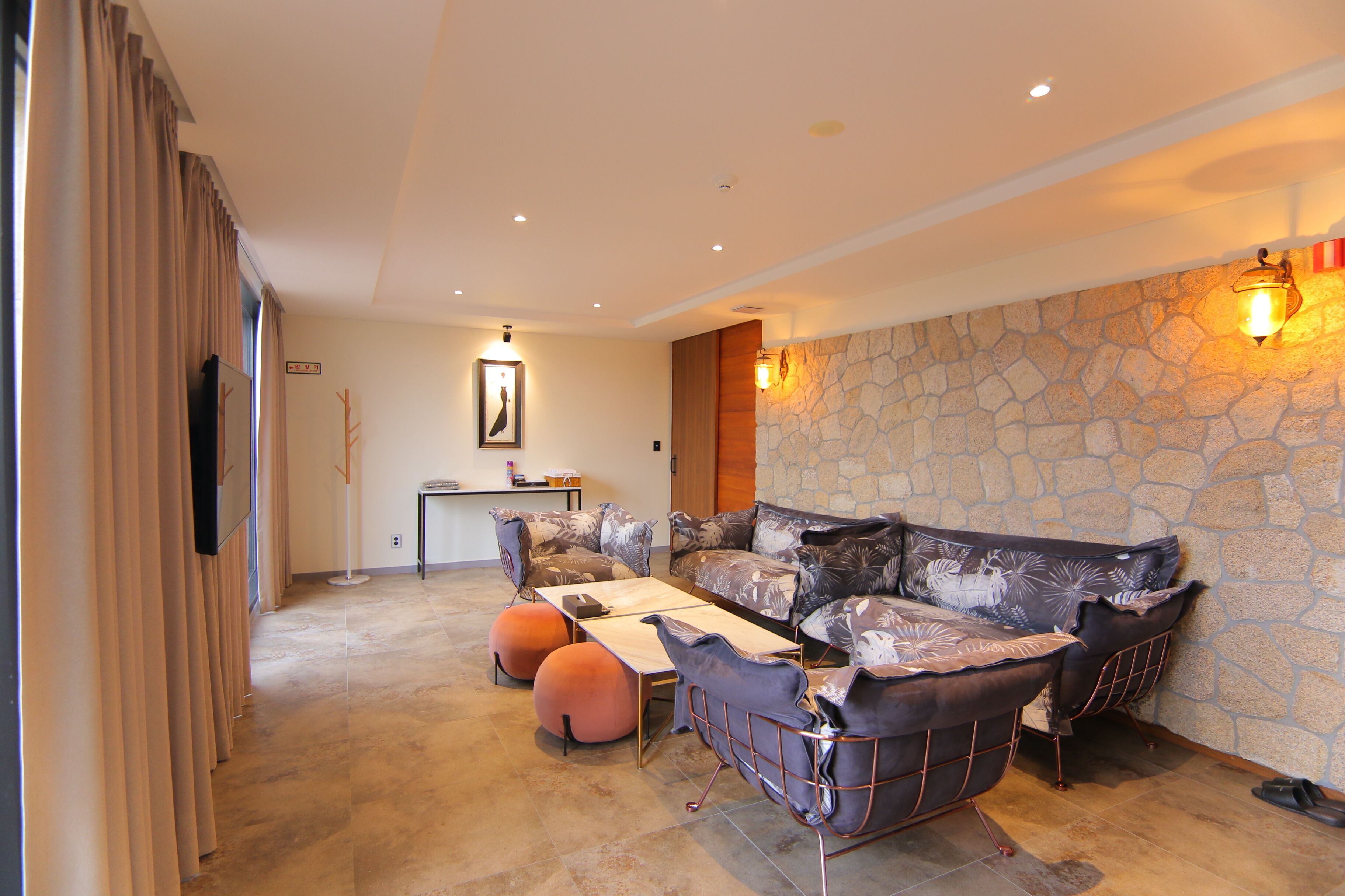 A modern living room with a stone accent wall, a sofa set, ottomans, and a dining table.