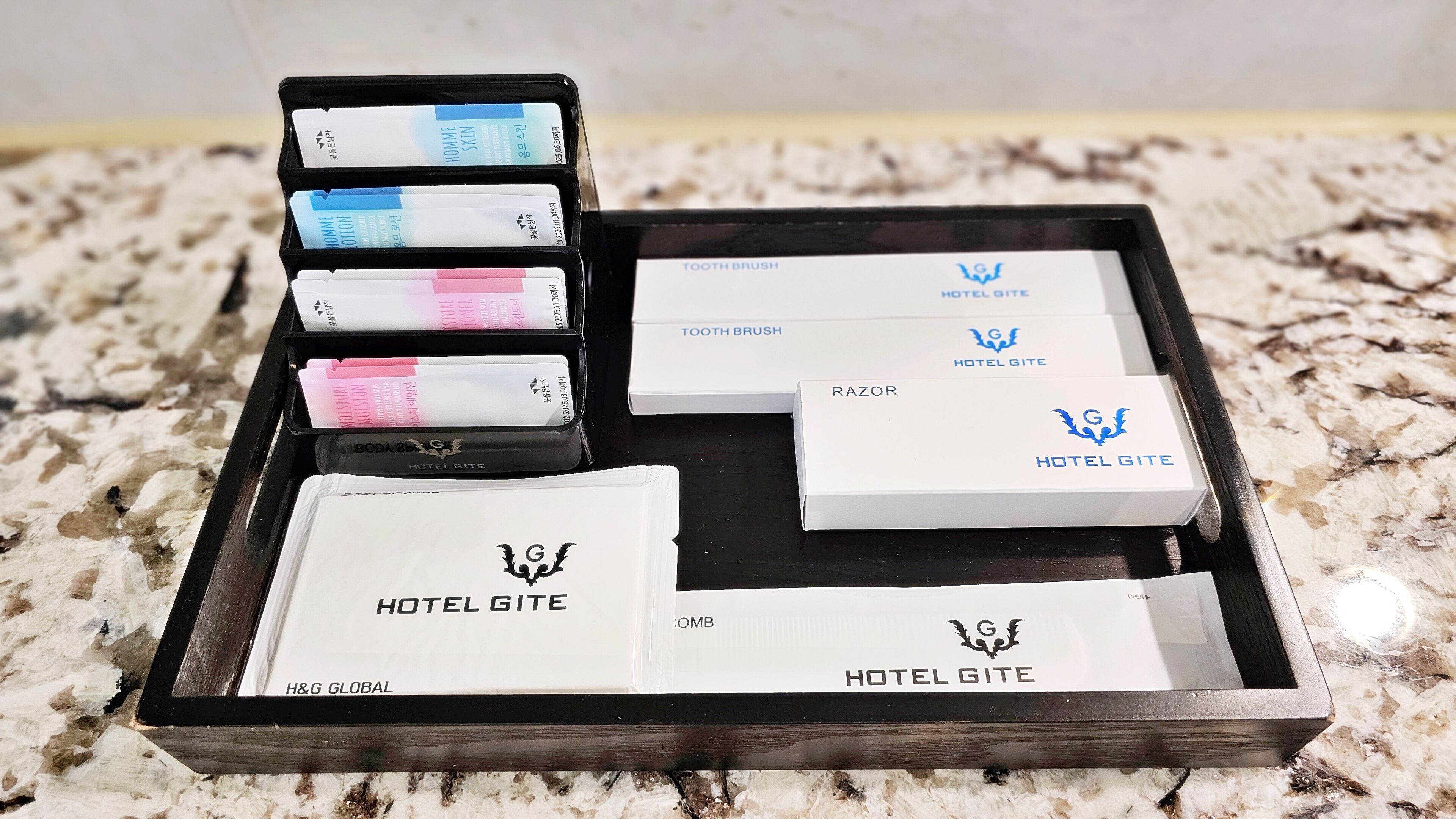 Uma bandeja com diversos produtos de higiene pessoal e itens com a marca do hotel.