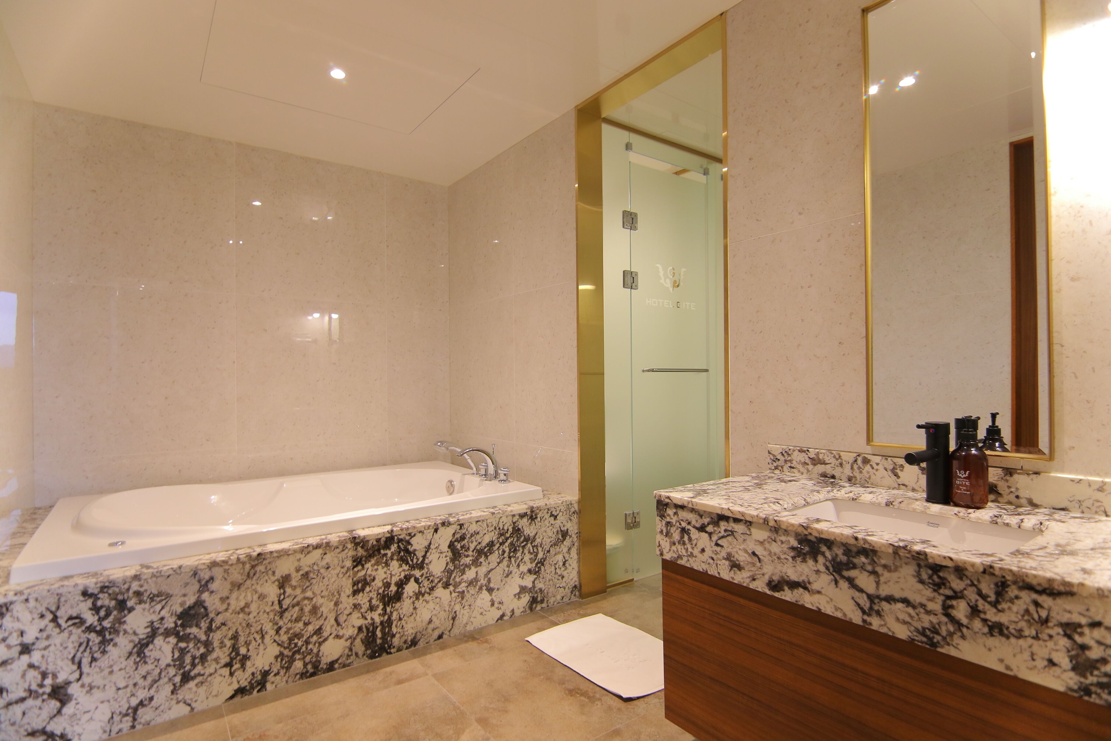 A modern bathroom with a marble sink, a large mirror, and a bathtub.