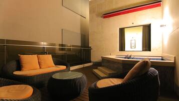 A modern spa area with wicker furniture, a glass balustrade, and a large mirror.