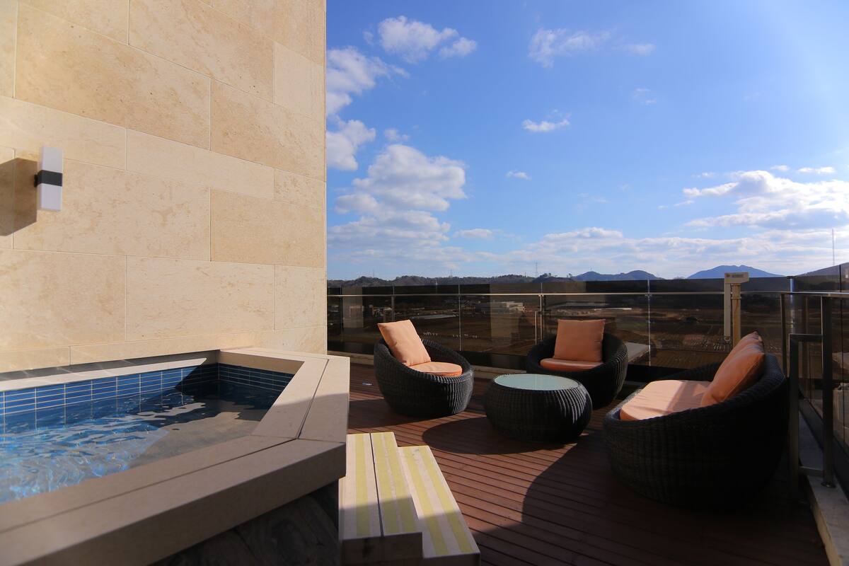 Una terraza en la azotea con jacuzzi, mobiliario de mimbre y vistas al paisaje.