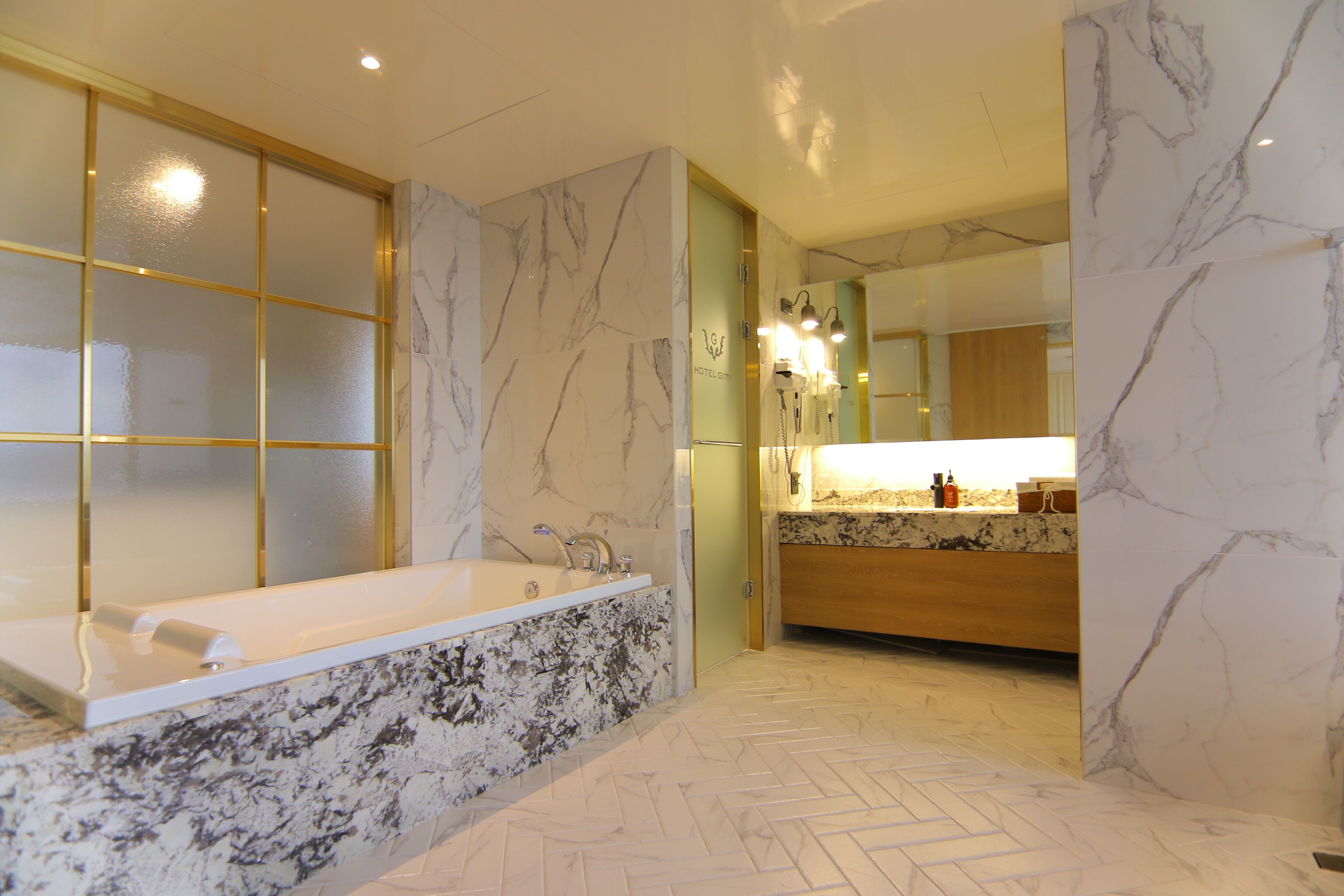 Un baño moderno con una bañera independiente, paredes de mármol y un patrón de suelo en espiga.