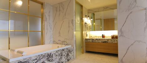 Une salle de bain moderne avec une baignoire sur pieds, des murs en marbre et un motif de parquet en chevrons.