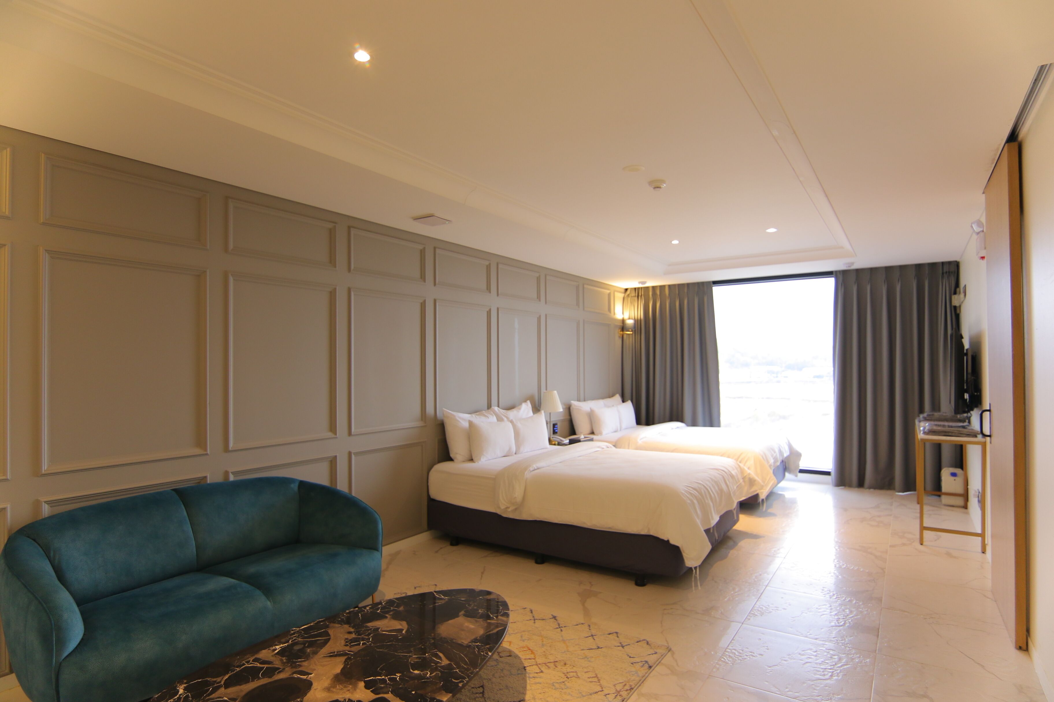 Camera d'albergo con un letto grande, una poltrona, una televisione e vista sull'esterno.