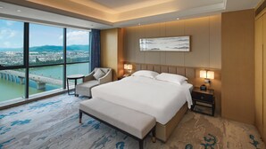 A spacious hotel room with a large bed, a seating area, a view of a cityscape, and a city bridge. - Galaxy Minyoun Langzhong Tianfu Hotel (Nanchong)