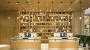 A reception area with a wooden panel ceiling, multiple shelves with decorative items, and two reception desks. - Galaxy Minyoun Langzhong Tianfu Hotel (Nanchong)