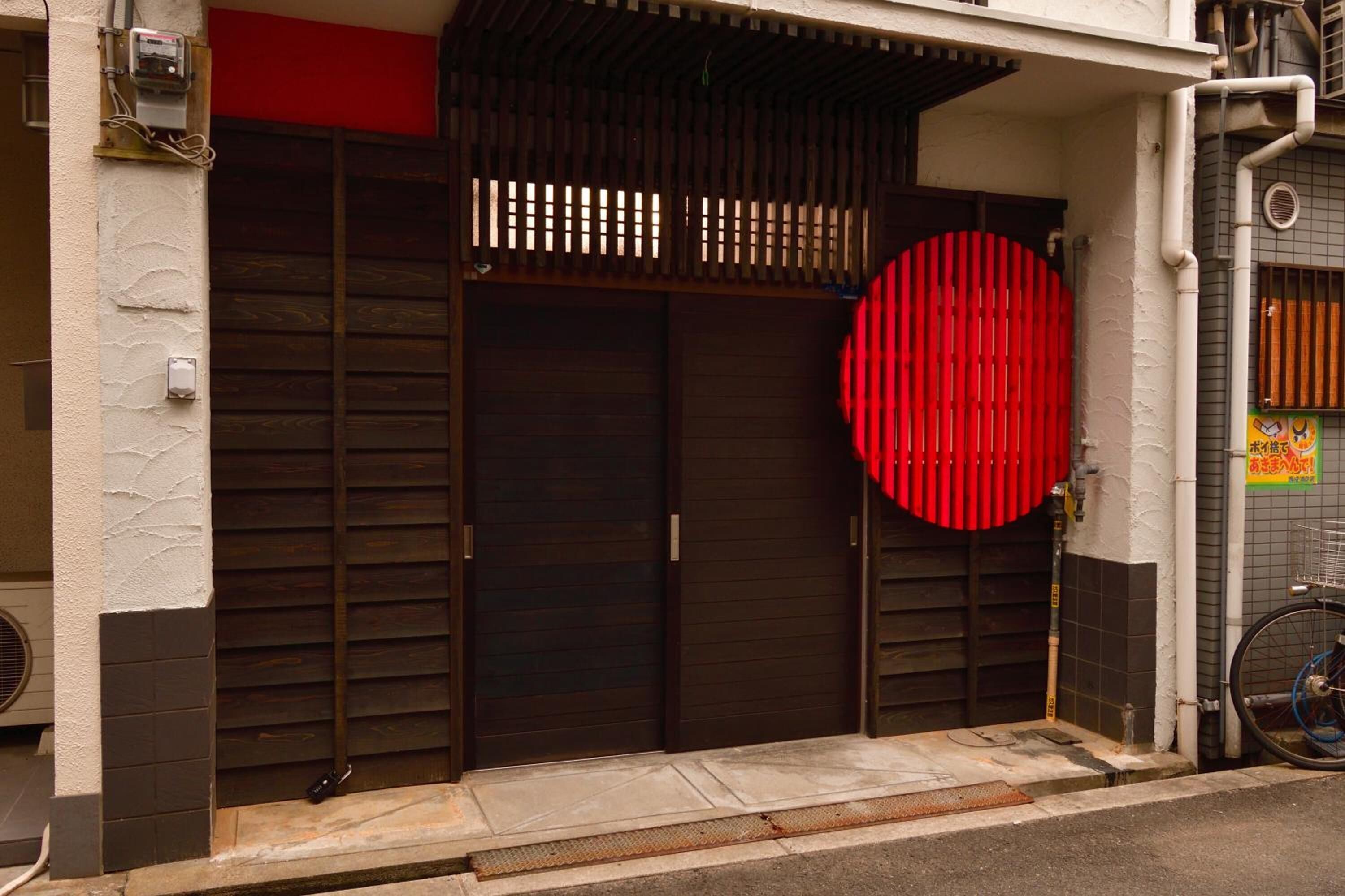 A building entrance with a large wooden door and a red circular feature.