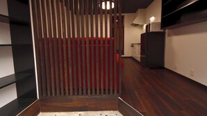 A narrow hallway with a wooden partition, a red cushioned bench, and a kitchen area in the background. - Machi de kurasu Tengachaya-1 (Osaka)
