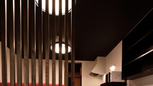A modern kitchen with dark wooden flooring, a red upholstered bench, and a black refrigerator. - Machi de kurasu Tengachaya-1 (Osaka)