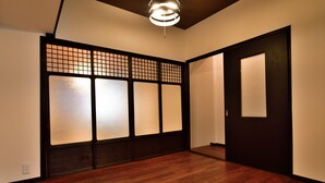 A room with wooden flooring, a sliding door, and a traditional Japanese-style partition with frosted glass panels. - Machi de kurasu Tengachaya-1 (Osaka)