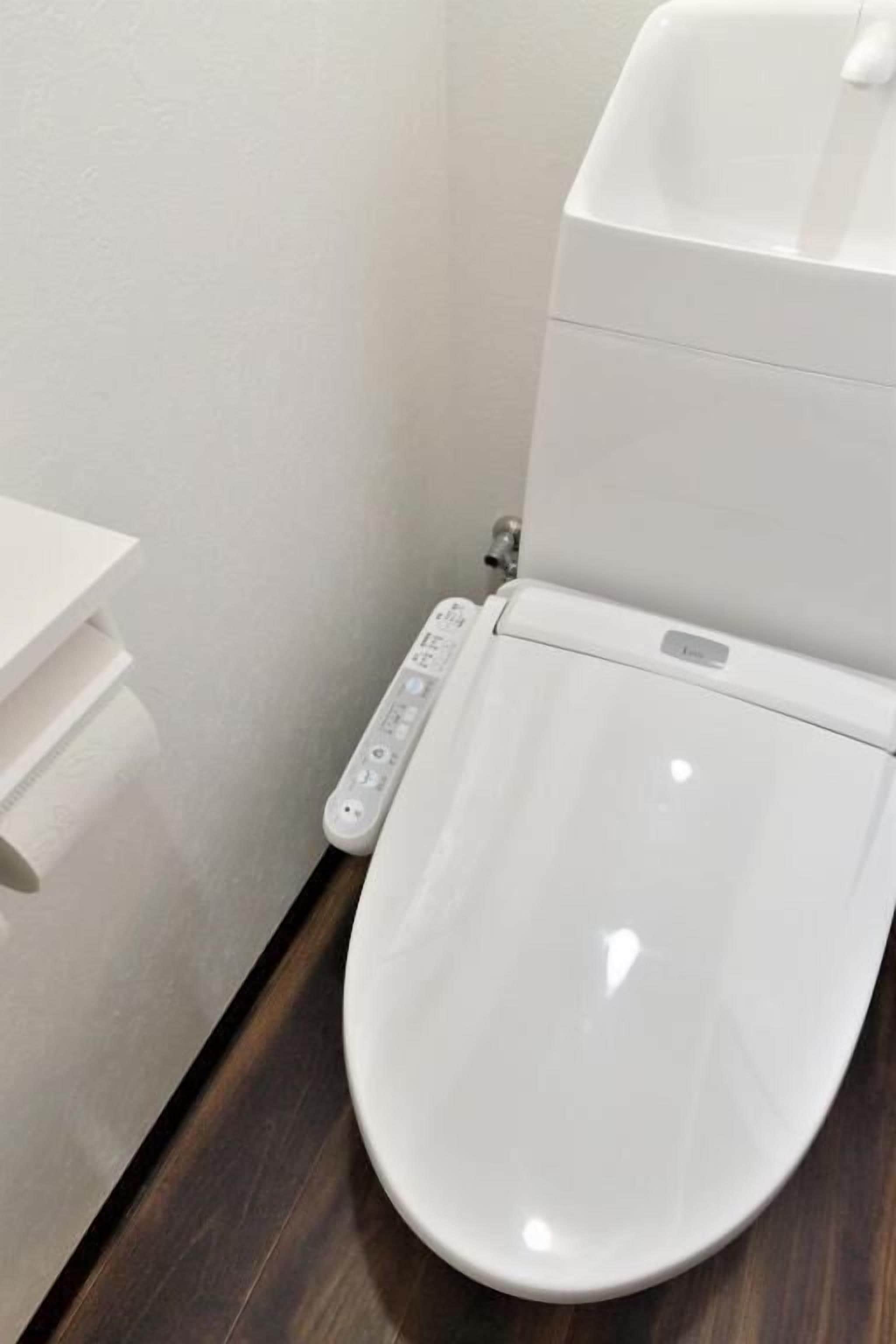 A white toilet with a control panel and a white sink.