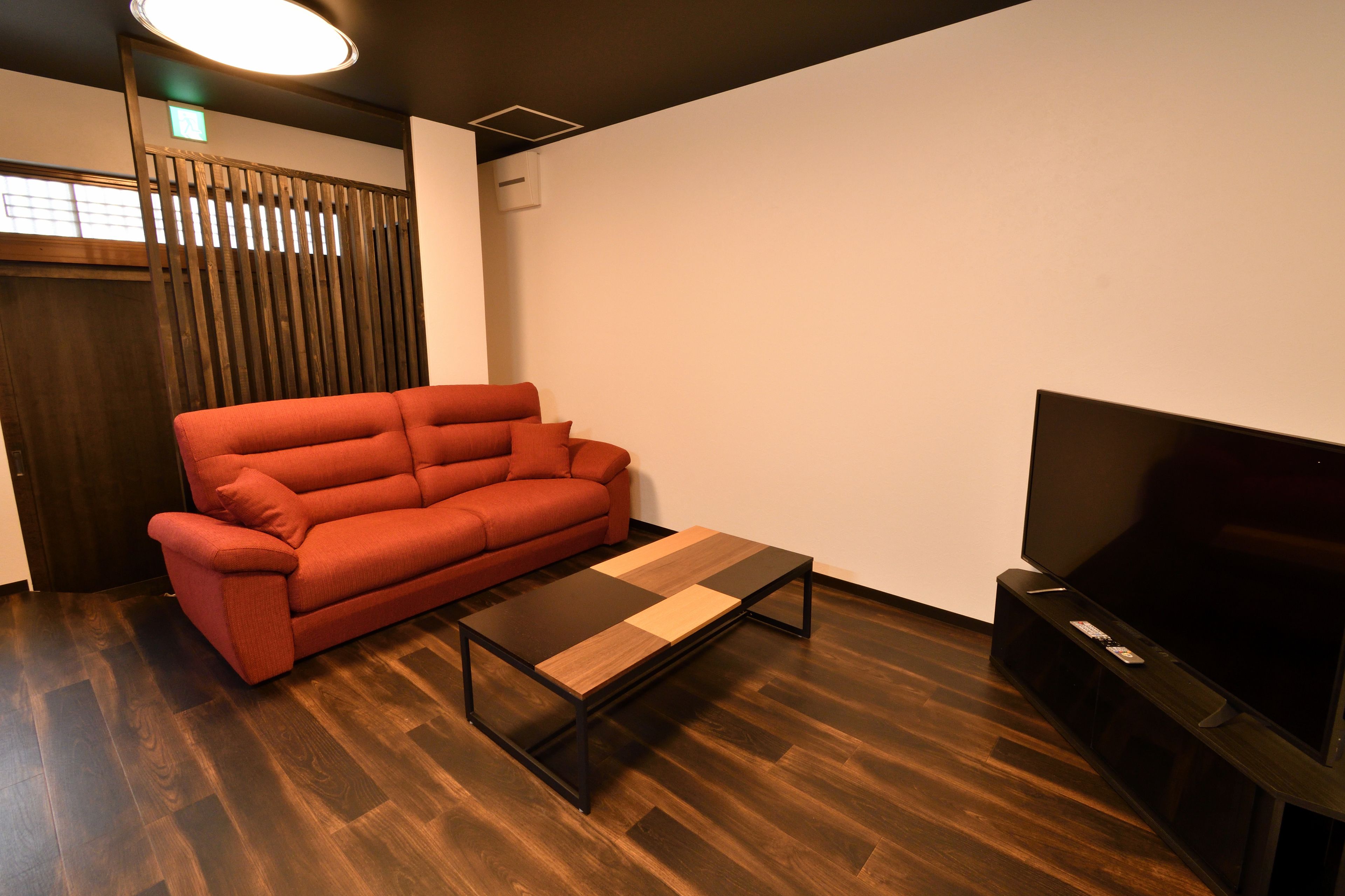 A modern living room with a red sofa, a wooden coffee table, and a flat-screen TV.
